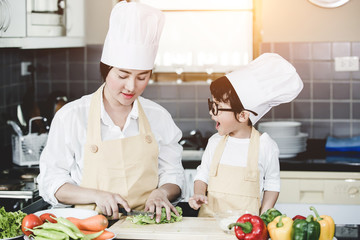 Happy family Asian woman young mother with son boy cooking healthy salad for the first time. first lesson and healthy lifestyle concept.