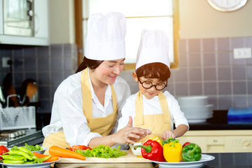 Happy family Asian woman young mother with son boy cooking healthy salad for the first time. first lesson and healthy lifestyle concept.