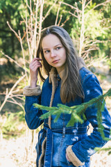 Young beautiful girl in a denim jacket in the park on a bright sunny spring day.