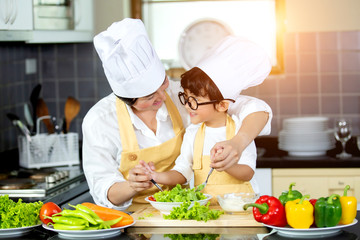 Happy family Asian woman young mother with son boy cooking healthy salad for the first time. first lesson and healthy lifestyle concept.