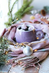 A cup of coffee with meringues and dessert, a warm scarf, Christmas decor, illuminations on a wooden windowsill,  home comfort concept, winter holidays