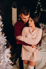 A guy with a girl is celebrating Christmas. A loving couple enjoys each other on New Year's Eve in a cozy home environment. New Year's love story.