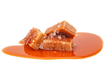 Delicious candies with salt and caramel sauce on white background. Salted caramel pieces.