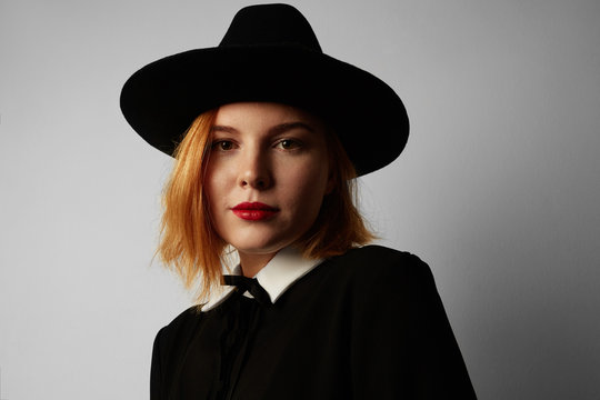 Close-up portrait of hipster young woman wearing black dress and hat. Isolated.