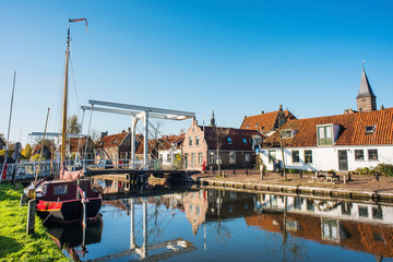 Fototapeta na wymiar Edam old town, Netherlands. Picturesque canal with boat in Waterland district near Amsterdam. Popular travel destination and tourist attraction