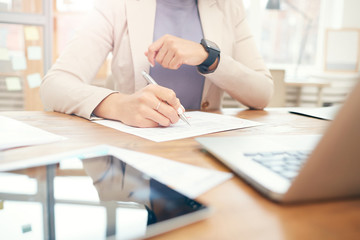 Cropped portrait of successful businesswoman checking wristwatch while working at desk in office, copy space