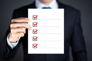 Checklist concept, Businessman checking mark on the check boxes with marker red © Worawut
