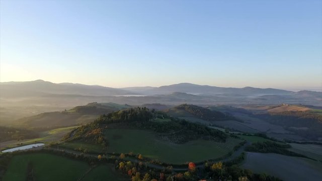 4k aerial drone right to left flight footage at early morning grazing light over the green Tuscany countryside hills between Volterra and Cecina.