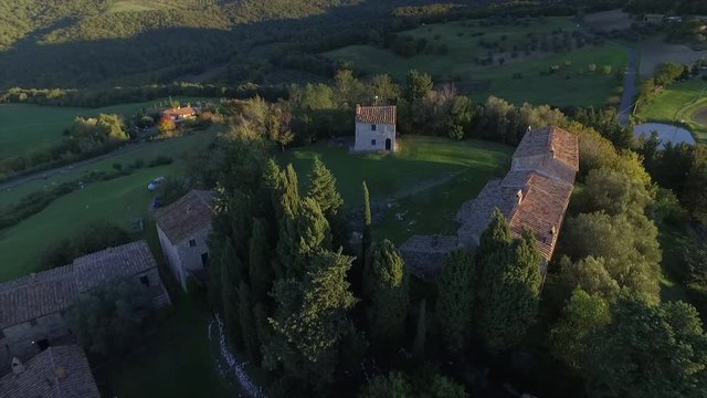 4k aerial  drone backward flight footage over the Tuscany countryside hills and the small ancien village of Gello near Volterra.