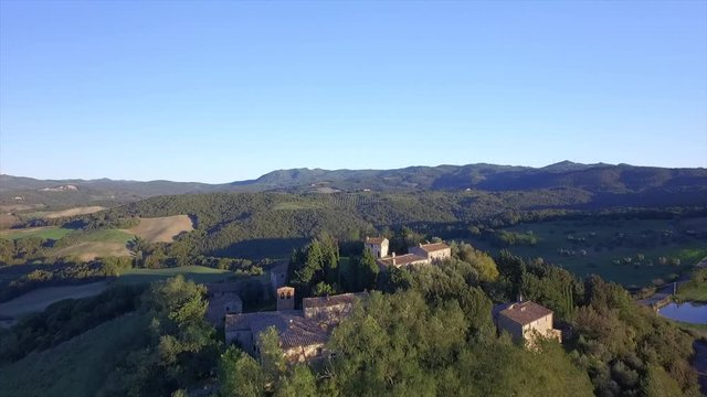4k aerial  drone forward flight footage over the Tuscany countryside hills and the small ancien village of Gello near Volterra.