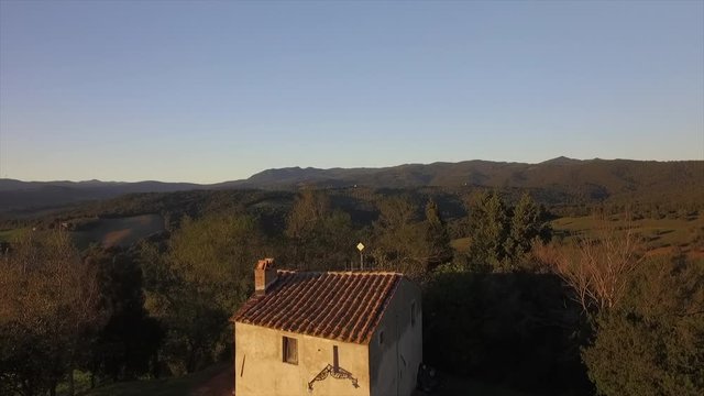 4k aerial  drone lowering flight footage over the Tuscany countryside hills and a beautiful small house in the ancien village of Gello near Volterra.