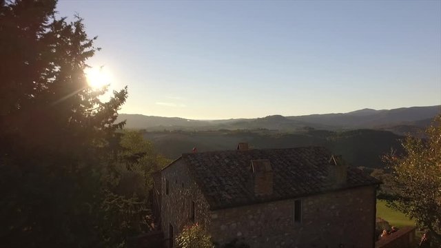 4k aerial  drone forward low flight footage at sunset time over the roof of an ancien house at Gello village in the Tuscany countryside near Volterra.