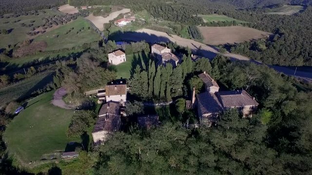 4k aerial  drone rising flight footage at midday time over the Tuscany countryside hills and the small ancien village of Gello near Volterra.