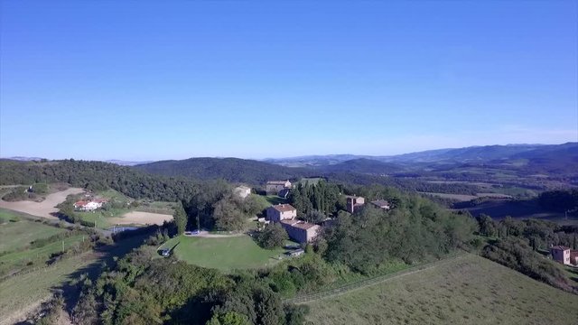 4k aerial  drone orbit flight footage at midday time over the Tuscany countryside hills and the small ancien village of Gello near Volterra, Italy.