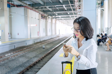 Asian businesswoman using mobile phone at train station