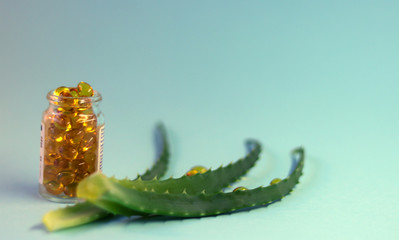 Aloe vera on a blue background and drug capsules in a vessel. Beauty and health concept