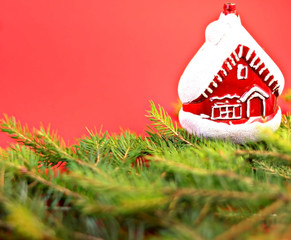 Christmas composition Christmas decorations, toy in the form of a house, fir branches with a red background. Flat design, side view, copy space. Place for text.