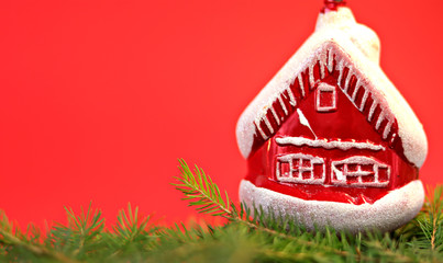 Christmas composition Christmas decorations, toy in the form of a house, fir branches with a red background. Flat design, side view, copy space. Place for text.