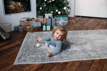 Little girl with gift boxes and christmas tree on background