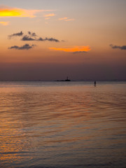 Silhouettes of people on sup boards in the rays of the setting sun against a background of clouds. Koh Phangan. Thailand.