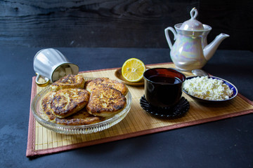 morning breakfast tea with cottage cheese and pancakes on a serving board, top view