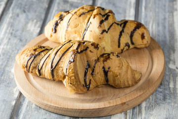 Tasty chocolate croissants on wooden background