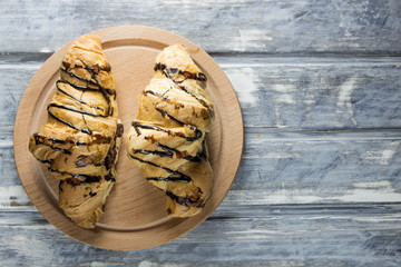 Tasty chocolate croissants on wooden background