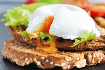 The yolk from a poached egg flows onto the bread.