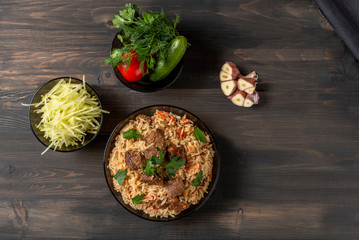 Oriental cuisine. National Uzbek pilaf with meat on a wooden table. Top view, copy space, flat lay.