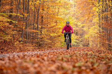 nice senior woman riding her mountainbike on the autumnal forest trails near Stuttgart, beautiful...