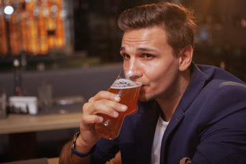 Close up of a handsome elegant man drinking delicious beer at the pub