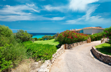 Stunning mediterranean coastline with green garden, blue sky and azure clear water, Sardinia, Italy