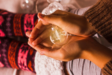 Christmas lights in palms. Cozy winter concept. Warm knitted socks