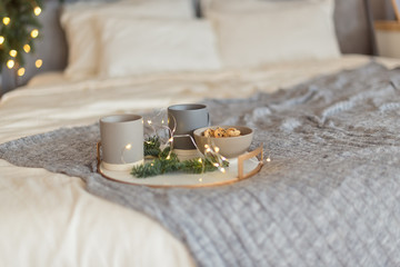 Cup of hot drink on bed on christmas morning. Cup of tea, Gifts with ribbon on bed and pine branch