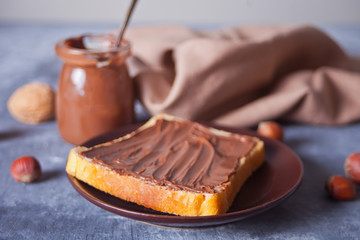 Bread toast with chocolate cream butter, jar of chocolate cream on the concrete background