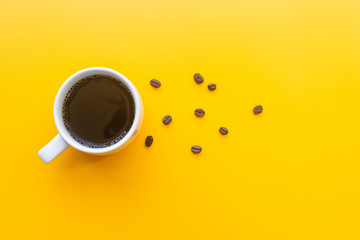 cup of coffee and coffee bean on yellow background. soft focus.