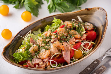 Delicious shrimps salad with fried bacon, vegetables and pine nuts. Tasty seafood salad.