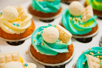 Close up vanilla cupcakes with varios cream cheese and candy in a paper box for gift