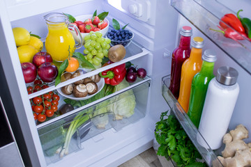 Food photography of a clean fridge filled with vegan foods such as fruits vegetables, juices and...