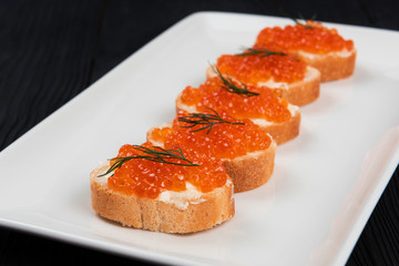 Naklejka na ściany i meble Sandwich with caviar and butter on a white plate.