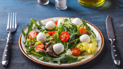 Fresh salad with arugula, lettuce,  cherry tomatoes and mozzarella cheese. Healthy and diet food