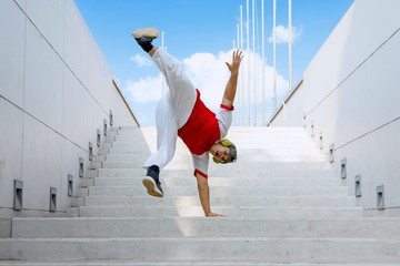 dancer wearing hat and headphone doing handstand