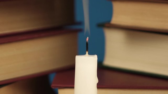 blowing out a candle on the background of a stack of books