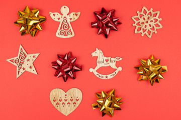 Holiday decorations. Composition made of red and gold bows, wooden Christmas tree toys on red background. top view, closeup