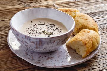 almond cream soup with pita bread served in a fleck ceramic pottery on wooden background