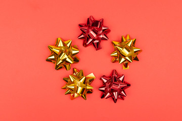 Obraz premium Holiday decorations, red and gold bows on red background. top view, closeup