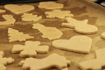 Homemade gingerbread cookies (cars, snowmen) on baking paper. Ready to oven. Christmas cookies. Family time. Concept of winter holidays. Xmas is here