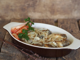 stew fried fish in a baking sheet on a wooden rustic table