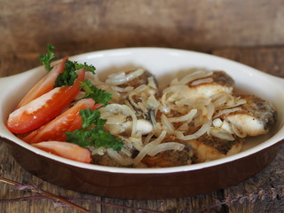 stew fried fish in a baking sheet on a wooden rustic table