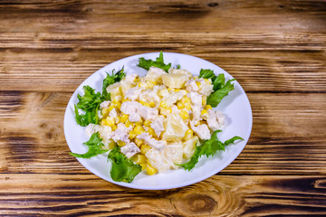 Festive salad with chicken breast, canned pineapple, cheese, sweet corn and mayonnaise on wooden table